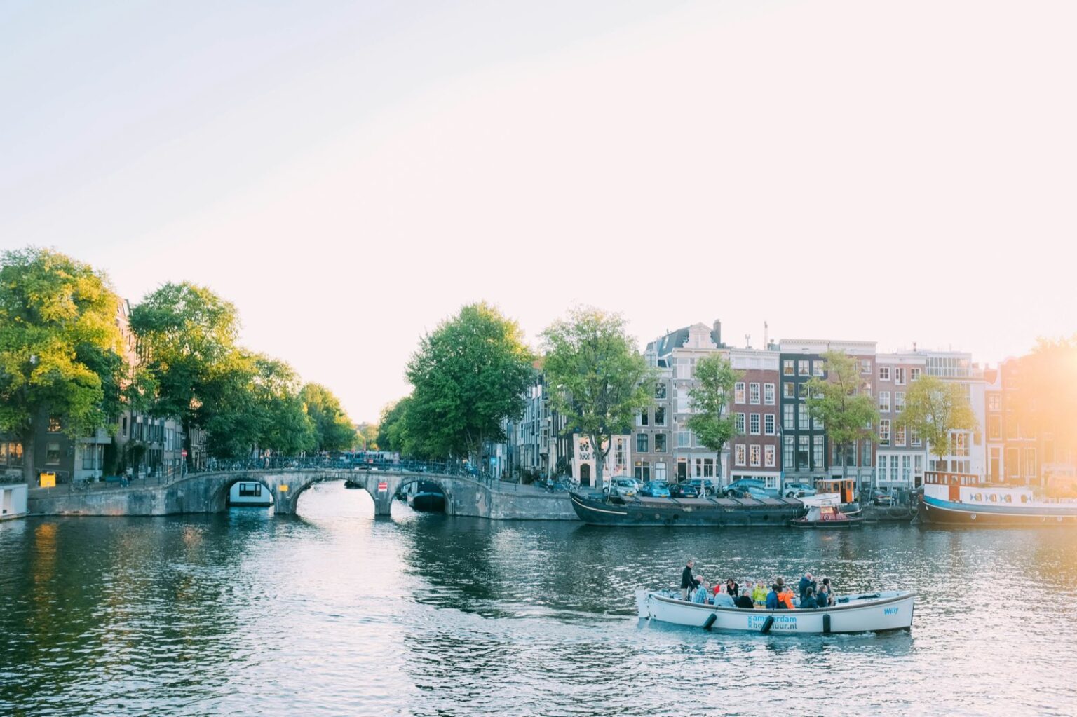 Elektrisch rondvaartbootje op een Amsterdamse gracht bij zonsondergang